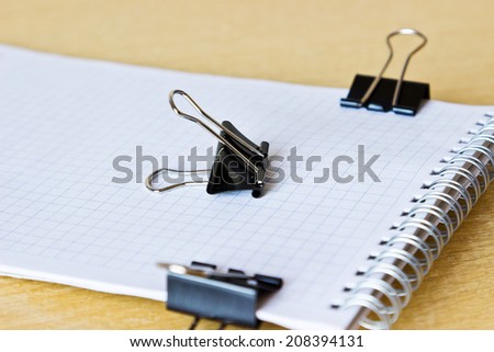 Checked notebook with paper clips on wooden table. Selective focus