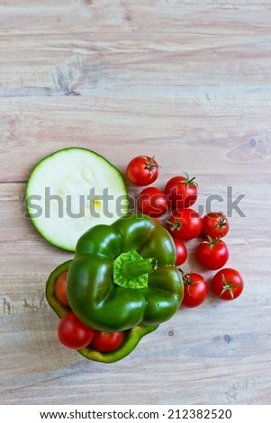 Small tomatoes in cut green pepper with zucchini slice. Vertical image