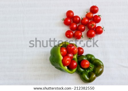 Small tomatoes in cut green pepper at white linen background. Horizontal image. Objects at the right part of image