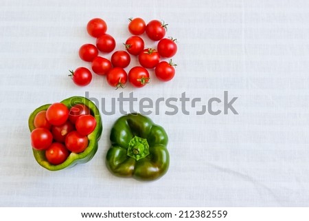 Small tomatoes in cut green pepper at white linen background. Horizontal image. Objects at the left part of image