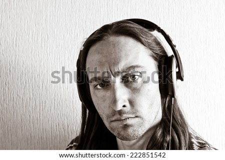 Handsome young long hair man with headphones looking at camera. Black and white image