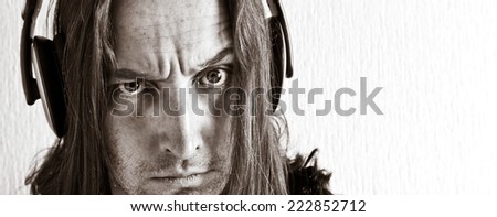 Angry long hair man with headphones looking at camera. Black and white image. Close up