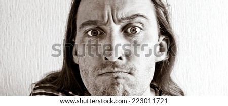 Angry long hair man portrait looking at camera. Black and white image