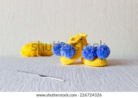 Colorful wool baby shoes with wool and knitting needles on white background