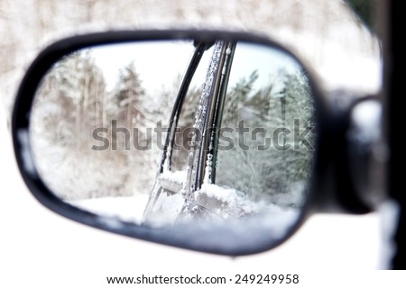 Reflecting of winter forest in a rear view car mirror