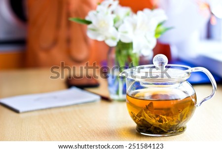 Celebrating composition: bouquet of white freesia flowers, smartphone, pen, teapot and notebook with painted heart. Selective focus on teapot. Horizontal image