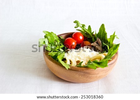 Salad of beef tongue, lettuce, tomatoes, cheese, scrambled eggs with cream and garlic sauce in wooden bowl. Selective focus