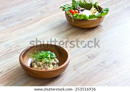 Two kinds of salads in wooden bowls: with vegetables and with  beef tongue. Focus on first bowl