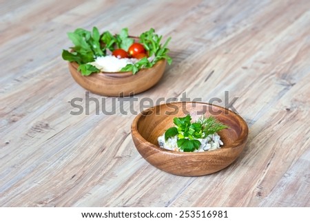 Two kinds of salads in wooden bowls: with vegetables and with  beef tongue. Focus on first bowl