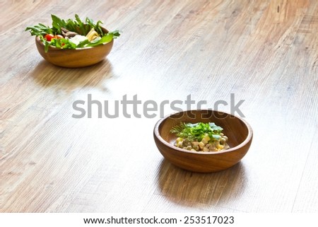 Two kinds of salads in wooden bowls: with vegetables and with  beef tongue. Focus on second bowl