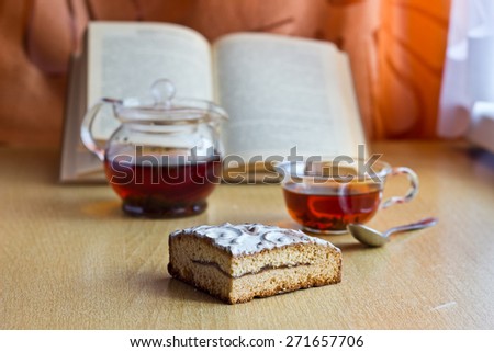 Morning still life with cake, glass cup of tea and open book. Shallow depth of field