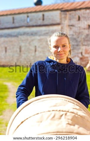 Happy mother with baby carriage. Ancient monastery at background