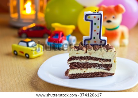 Baby first birthday party. Focus on cake with candle. Blurred multicolored background
