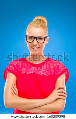 Confident young woman. Portrait of a beautiful woman in black glasses smiling at camera. Studio shot isolated on blue.