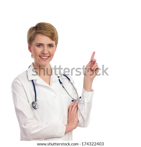 Female doctor pointing at copy space. Waist up studio shot isolated on white.