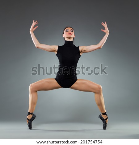 Modern ballet dancer. Female ballet dancer in a pointe shoes posing on her toes. Full length studio shot on gray background.