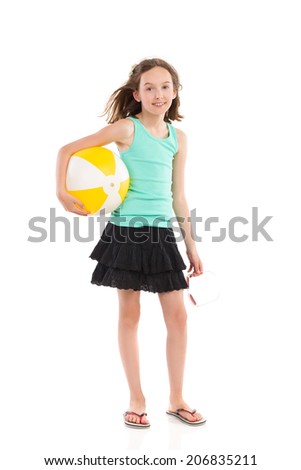 Girl in green shirt and black skirt standing and holding a beach ball under her arm. Full length studio shot isolated on white.