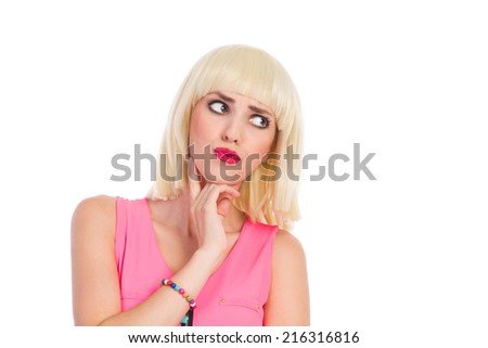 Uncertainty. Grimacing blonde young woman holding hand on chin and looking away. Head and shoulders studio shot isolated on white.