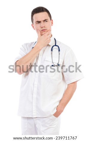 Thinking young male doctor holding hand on chin and looking away. Three quarter length studio shot isolated on white.