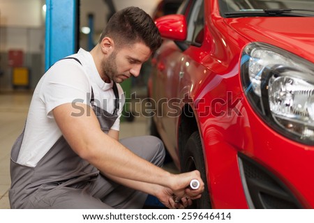 Changing the wheel. Focused mechanic using a torque wrench