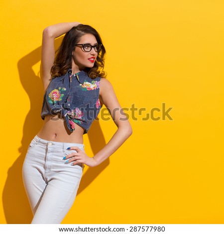 Young Woman Against Sunny Yellow Wall. Three quarter length studio shot on yellow background.