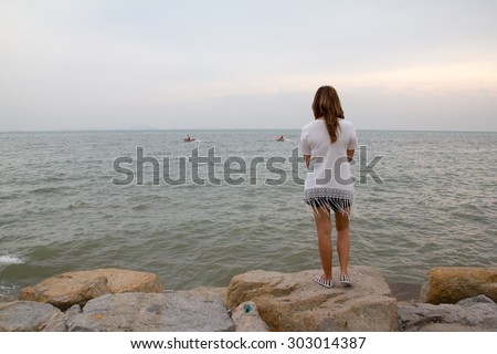 Alone women feel sad stand on the rock look sea