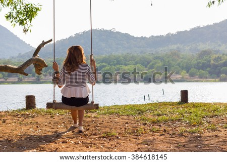 Alone woman sit on swing feel sad in park
