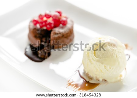 Chocolate fondant with ice cream on a white plate on a white table. Liquid center is flowing out. Focus on ice cream
