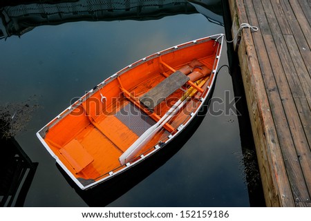 Orange boat in peaceful  water tethered to a dock clear water, row boat, orange