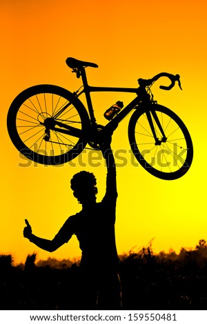 a cyclist raising his roadbike with his right hand thumbs up silhouette