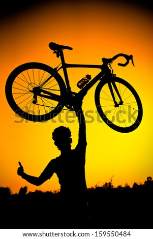 a cyclist raising his road bike with his right hand thumbs up silhouette