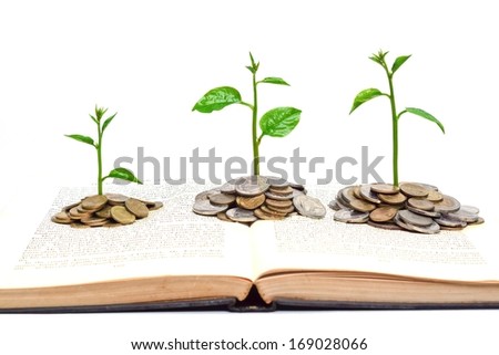 trees growing from books with coins / A big open book with coins and tree. \