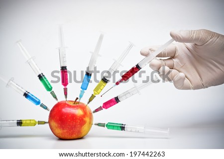 Injection into red apple - Genetically modified fruit and syringe with colorful chemical GMO food