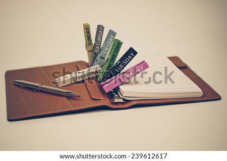 open notebook with a pen and wooden clips with days in a week on isolated background