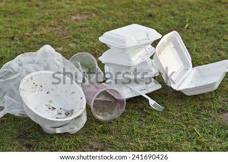foam and plastic food container on grass field - environmental problems