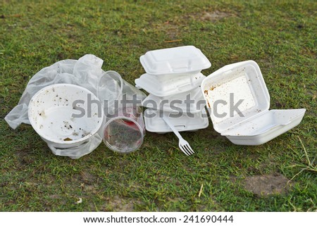 foam and plastic food container on grass field - environmental problems