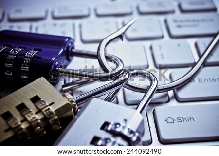 security locks with a fish hook on computer keyboard / security breach concept / phishing