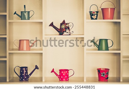 Shelf decoration with colorful gardening tools - watering cans, pail, bucket