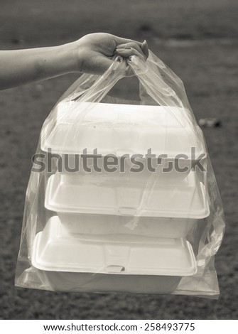 hands holding a clear plastic bags containing three foam containers