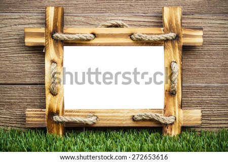 old wooden picture frame with white space on green grass floor with wood background