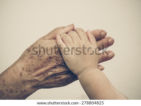 hand of a young baby touching old hand of the elderly