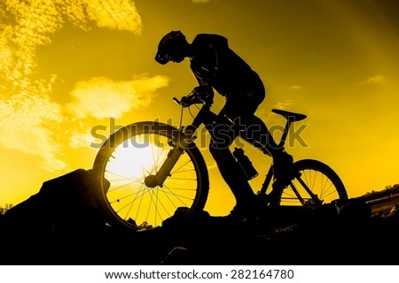a cyclist with his mountain bike with sunset silhouette