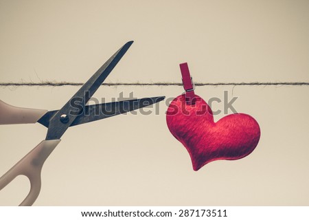 Scissors cutting a rope with a red heart - Broken heart concept