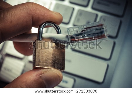 hand holding a security lock with lan wire on computer keyboard