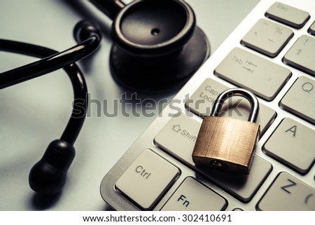 a stethoscope over computer keyboard with a security lock -computer system check and maintenance concept