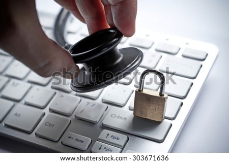 hand holding  a stethoscope over computer keyboard with a security lock - computer system check and maintenance concept