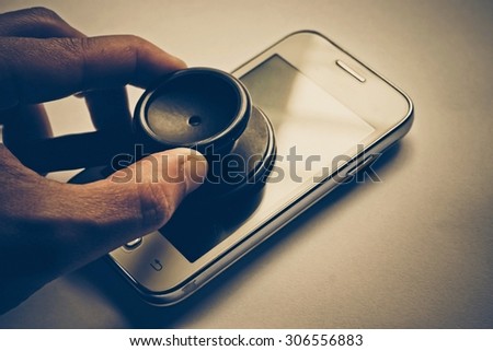 hand using a stethoscope to check smartphone system - checking security on smartphone concept