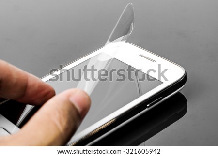 hand laying scratch protective film on a smartphone screen