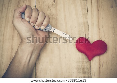 hand with a knife stabbing into a red heart