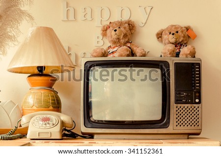 happy corner of a house with decoration of words saying think happy be happy, bear dolls, old telephone, vase, pot, lamp, plant, bird feather, basket, television